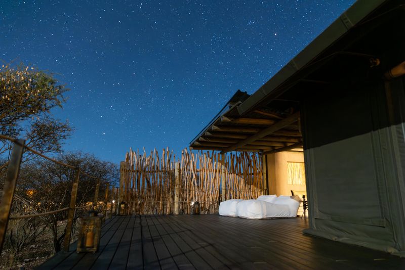 A large safari viewing deck with two loungers under a star-filled blue sky