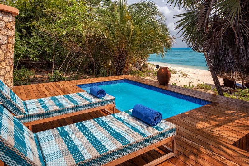 A luxurious beachfront villa at Anantara Bazaruto Island Resort, featuring a private pool, thatched roof, and stunning ocean views with white sand and palm trees.