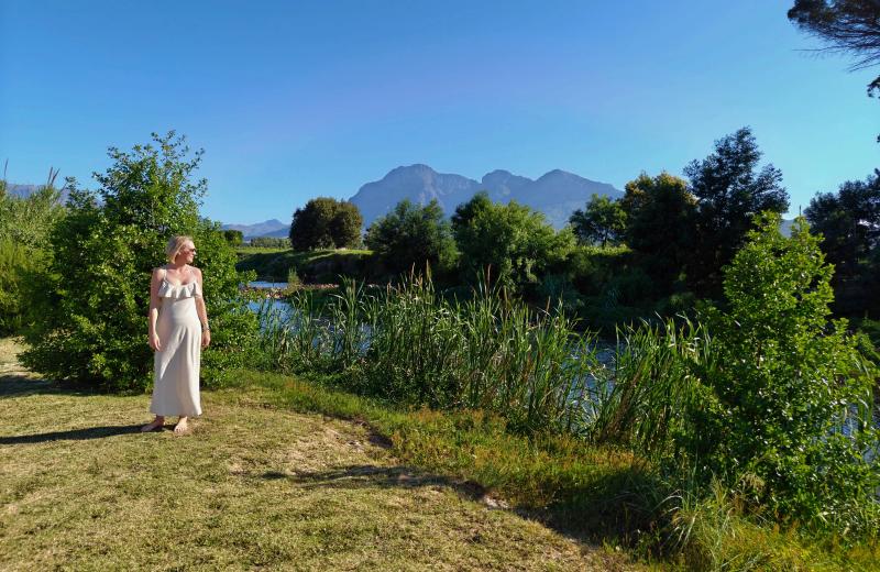 A woman stands next to a river in Franschhoek, one of the best places to visit in the Cape Winelands