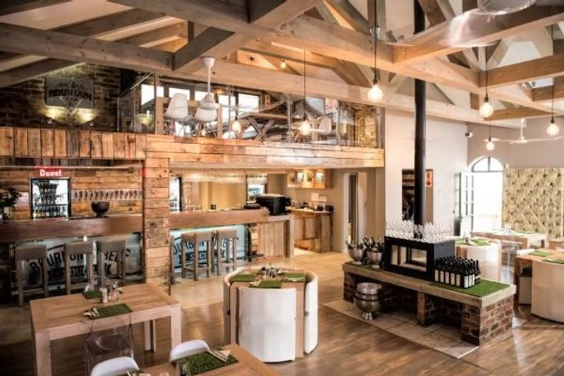 Rustic restaurant interior with wooden beams, a bar, and an upstairs mezzanine seating area