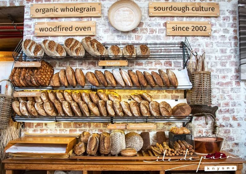 Shelves of freshly baked sourdough loaves and fougasse displayed against a brick wall bakery