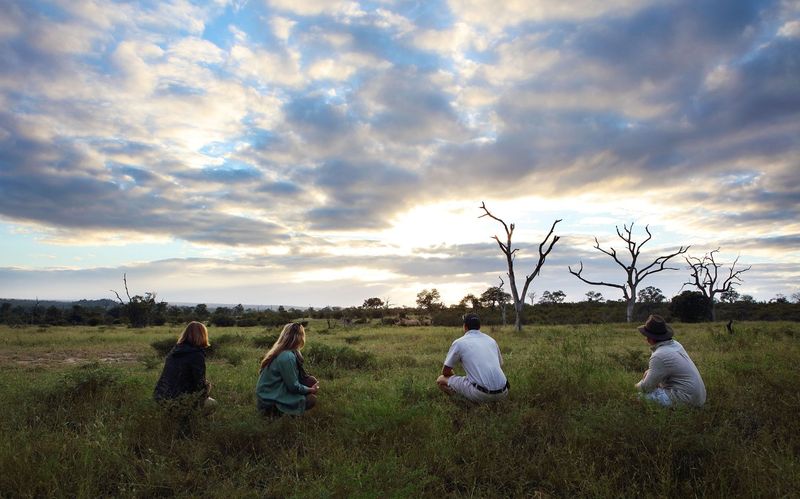 Four individuals crouching among the savannah grasslands