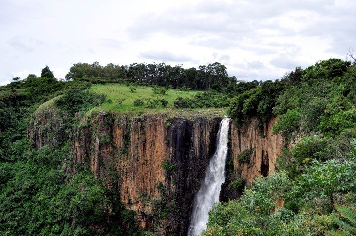Ein Wasserfall zwischen rötlich-orangenen Felsen und grüner Natur