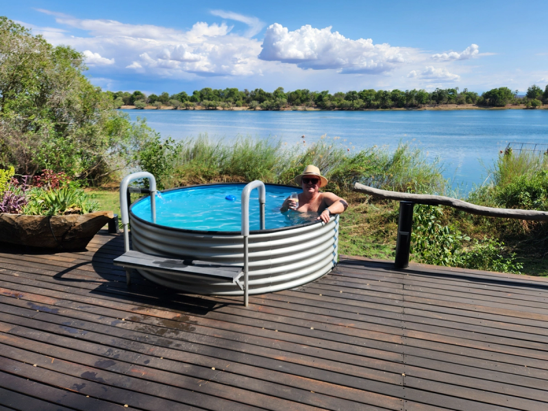 Ian Kriek, a Rhino Africa travel consultant sitting in a plunge look with a view of a river in the background.