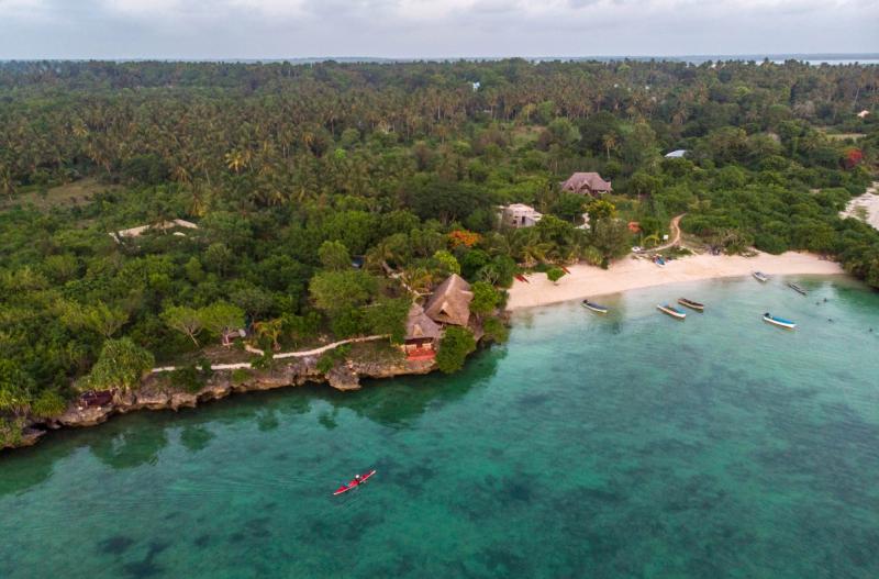 A kayak glides on blue ocean waters towards the shore of Zanzibar, one of the best East Africa holiday destinations.