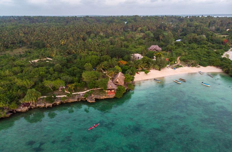 A kayak glides on blue ocean waters towards the shore of Zanzibar, one of the best East Africa holiday destinations.