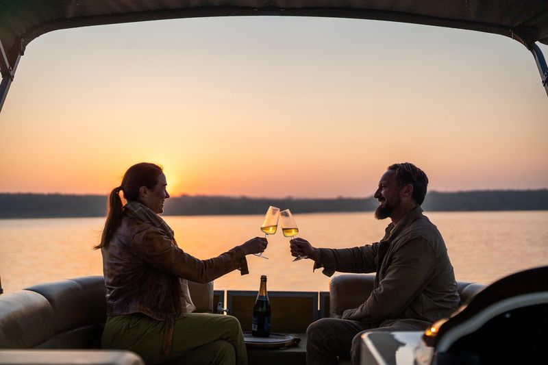 Two guests enjoy a glass of wine on a bopat cruise while on a Rwanda safari