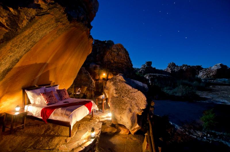Lit à ciel ouvert au cœur des formations rocheuses de grès de la Star Suite de Kagga Kamma, dans le Cederberg, sous un ciel constellé d’étoiles.