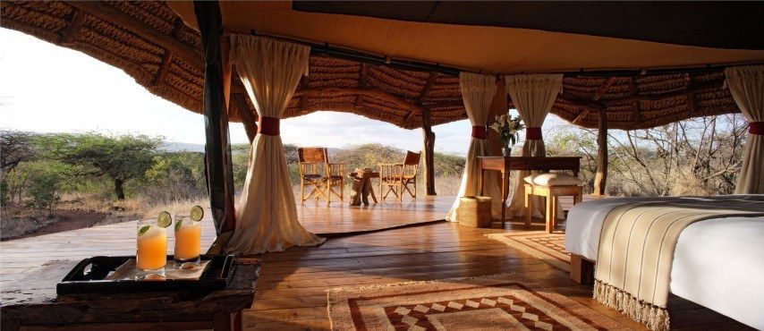 Room interior at Lewa Safari Camp, featuring a comfortable bed and safari-inspired furnishings.