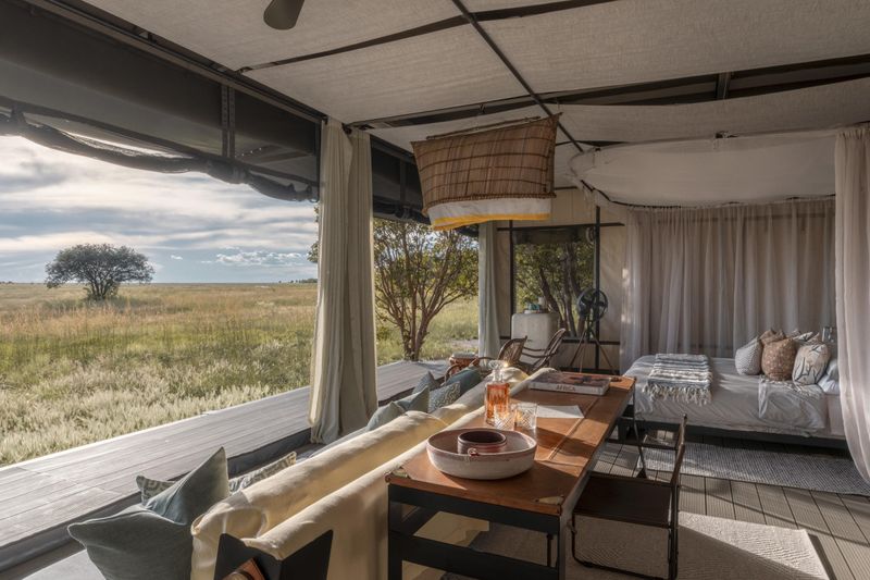 An open-sided safari tent reveals a softly furnished interior overlooking wide grasslands, embodying immersive destinations for responsible travel.