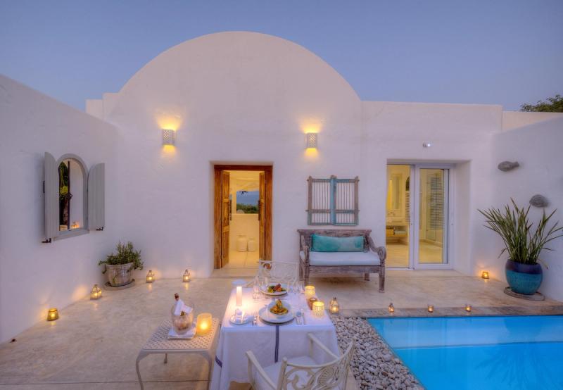 One of Santorini Mozambique's whitewashed Mediterranean-styled villas with a private swimming pool and candlelit outdoor dining area.