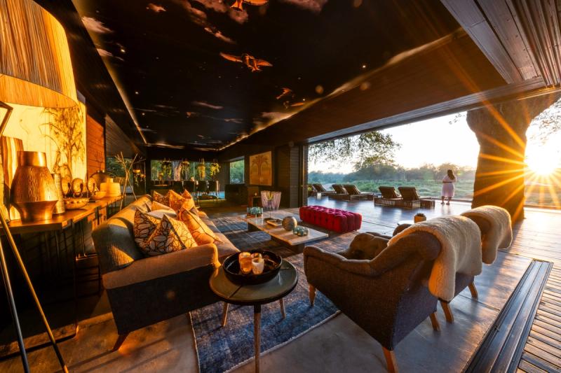 A golden-lit lounge at Silvan Safari opens onto a sun-drenched deck and wilderness beyond