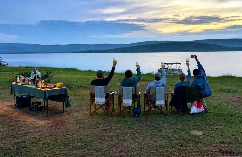 Travellers raise their glasses during sundowners beside Lake Rwanyakazinga in Akagera National Park.