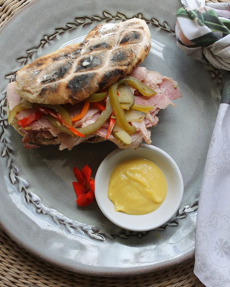 Grilled flatbread sandwich with ham and peppers served with mustard sauce on a plate