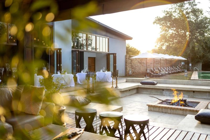 La terrasse du Karongwe Becks Safari Lodge, équipée de tables pour les repas en plein air, de fauteuils, d'un foyer extérieur et d'une piscine.