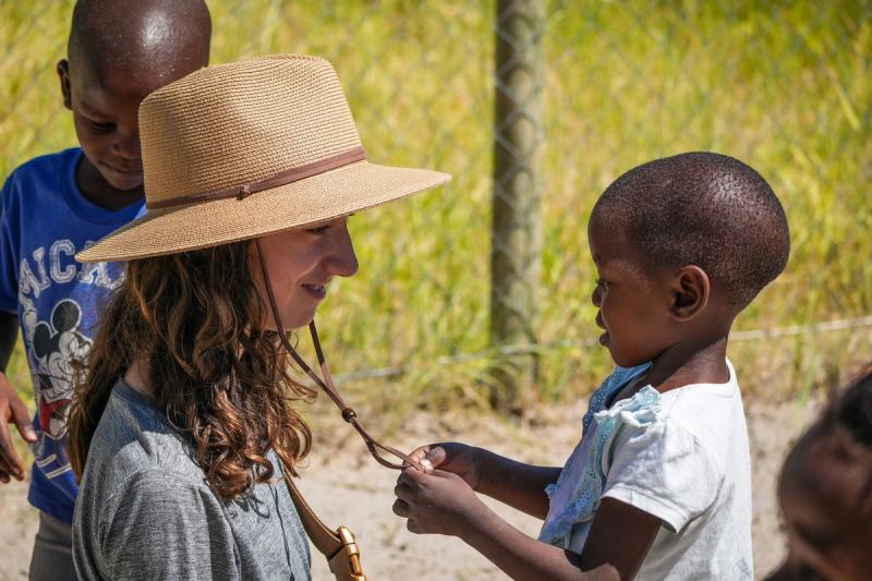 Woman interacting with children during community visit with ABC Camps