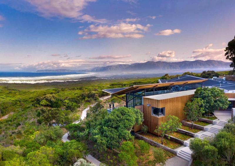 Panoramic view from Grootbos Private Nature Reserve overlooking fynbos vegetation, rolling mountains, and the coastline of Walker Bay in South Africa.