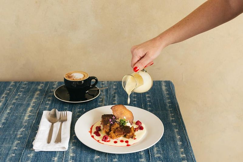 Frau gießt Vanillesoße über Malva Pudding