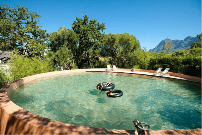 Piscine extérieure turquoise et montagnes en arrière plan à Babylonstoren.