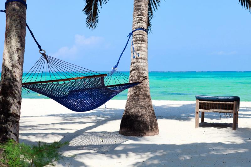 Eine Hängematte zwischen zwei Palmen an einem weißen Sandstrand auf Sansibar