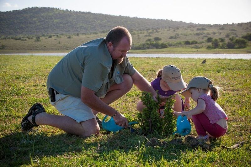 Vater pflanzt mit Töchtern einen Speckbaum im Kwandwe Private Game Reserve