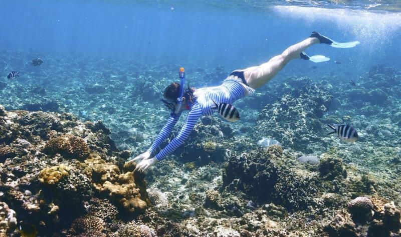 Woman snorkelling in Seychelles’ clear waters – an example of impactful travel experiences that promote marine conservation and eco-tourism