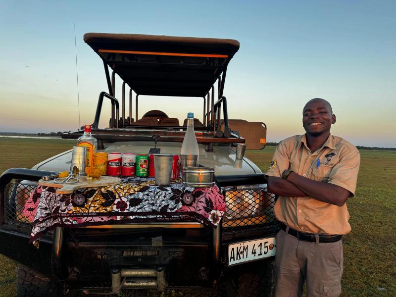 A man poses in front of a safari vehicle for sundowners in Gorongosa National Park