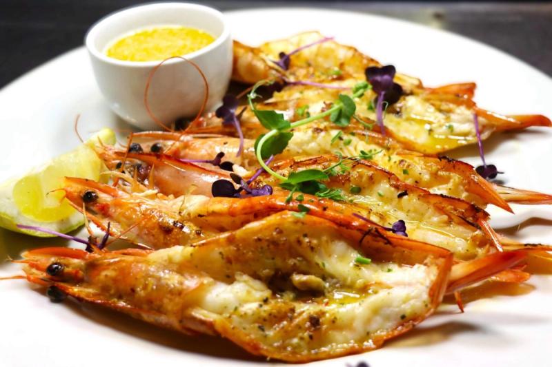 Butterflied grilled prawns garnished with microgreens served with lemon and dipping sauce