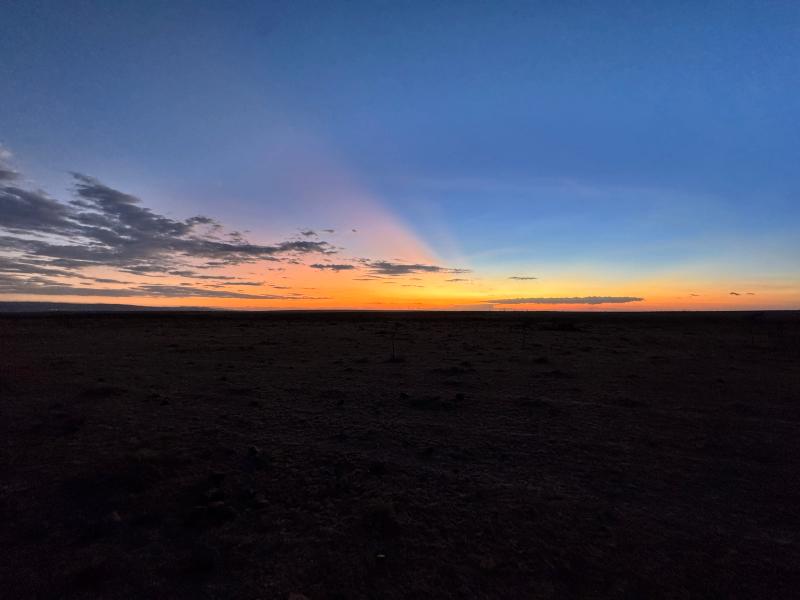 Wide panoramic view across the flat savannah plains of the Maasai Mara under a fading dusk sky.