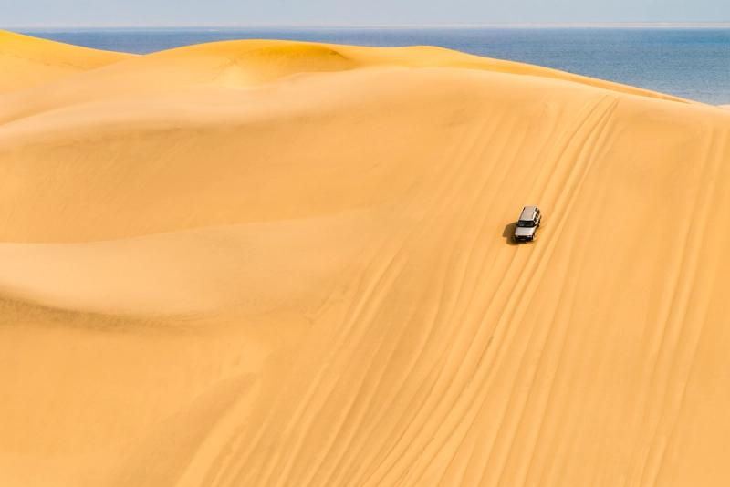 Car driving down massive dune in Sandwich Harbour in Namibia
