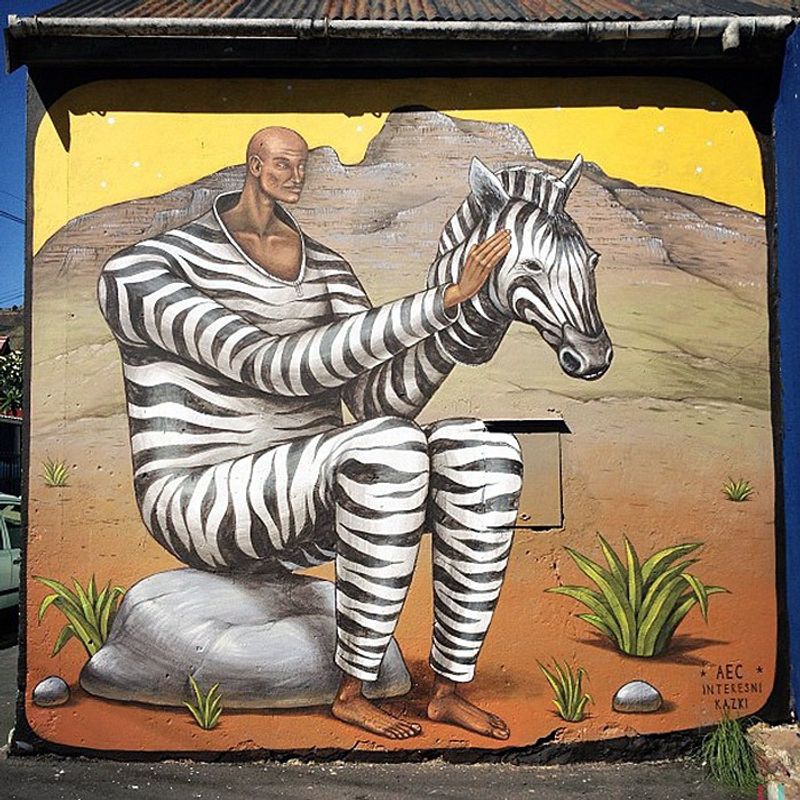 Mann in Zebrakostüm sitzt auf einem Stein - Straßenkunst in Kapstadt
