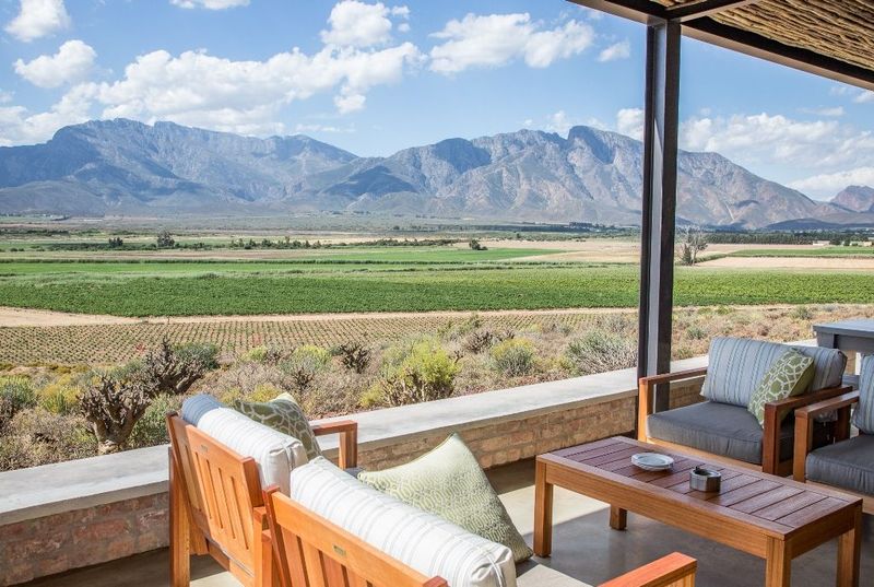 Covered patio with wooden seating overlooking vineyards and mountains in the Robertson valley