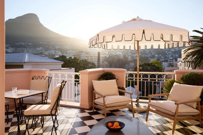A sunlit terrace with cushioned chairs and mountain views at one of the luxury hotels in Cape Town
