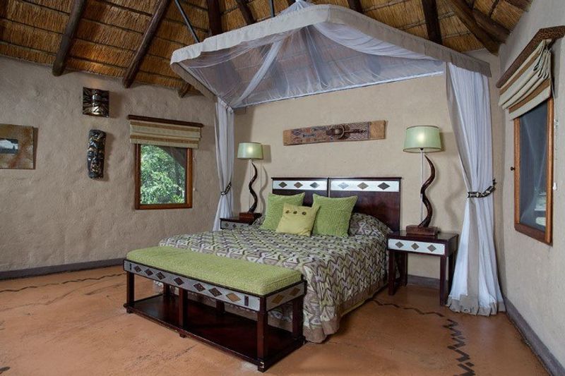Ein Doppelbett mit Moskitonetz in einer traditionellen Safari-Lodge