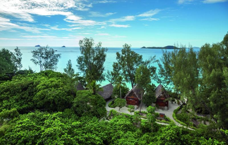 Thatched beachfront villas peek through lush forest on a remote island, offering the perfect escape for African travel in May.