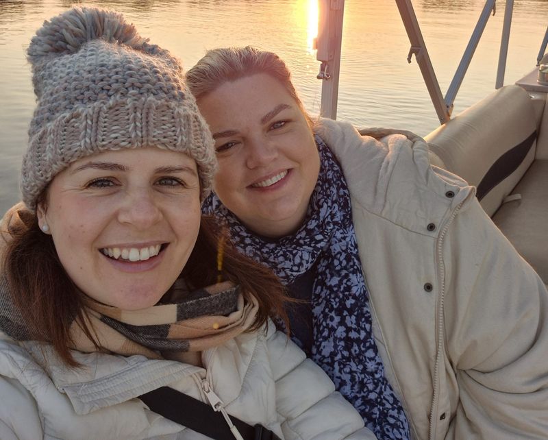 Our travel experts Ali and Kristy wearing warm jackets on an early morning river cruise