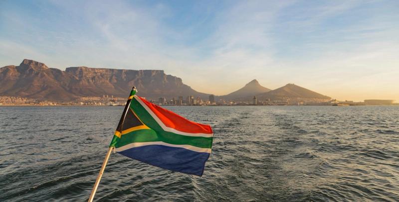 South African flag in the foreground with backdrop of Table Mountain from the ocean