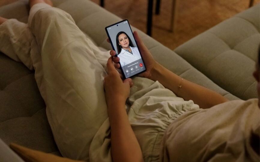 Jente ligger i sofaen og snakker med en lege på facetime på mobilen