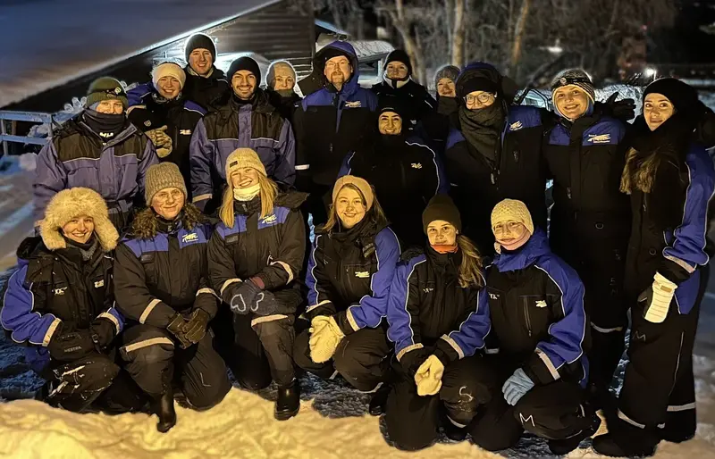 Bilder av en gjeng med studenter fra rekrutteringsavdeling ser i kamera og smiler kledd for hundekjøring i Tromsø