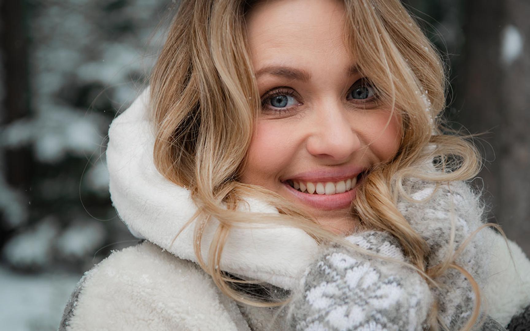 Nærbilde av en kvinne med skjerf og strikkevotter.