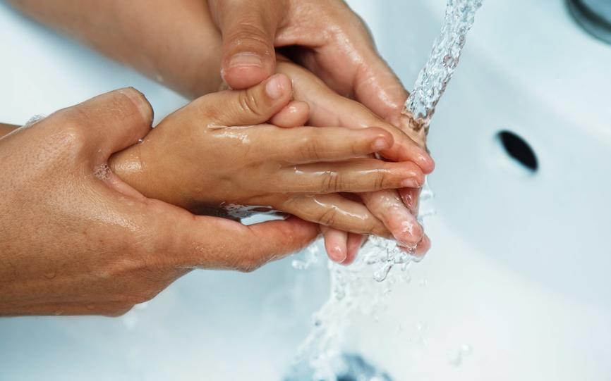 Voksen og barn som vasker hendene under krana