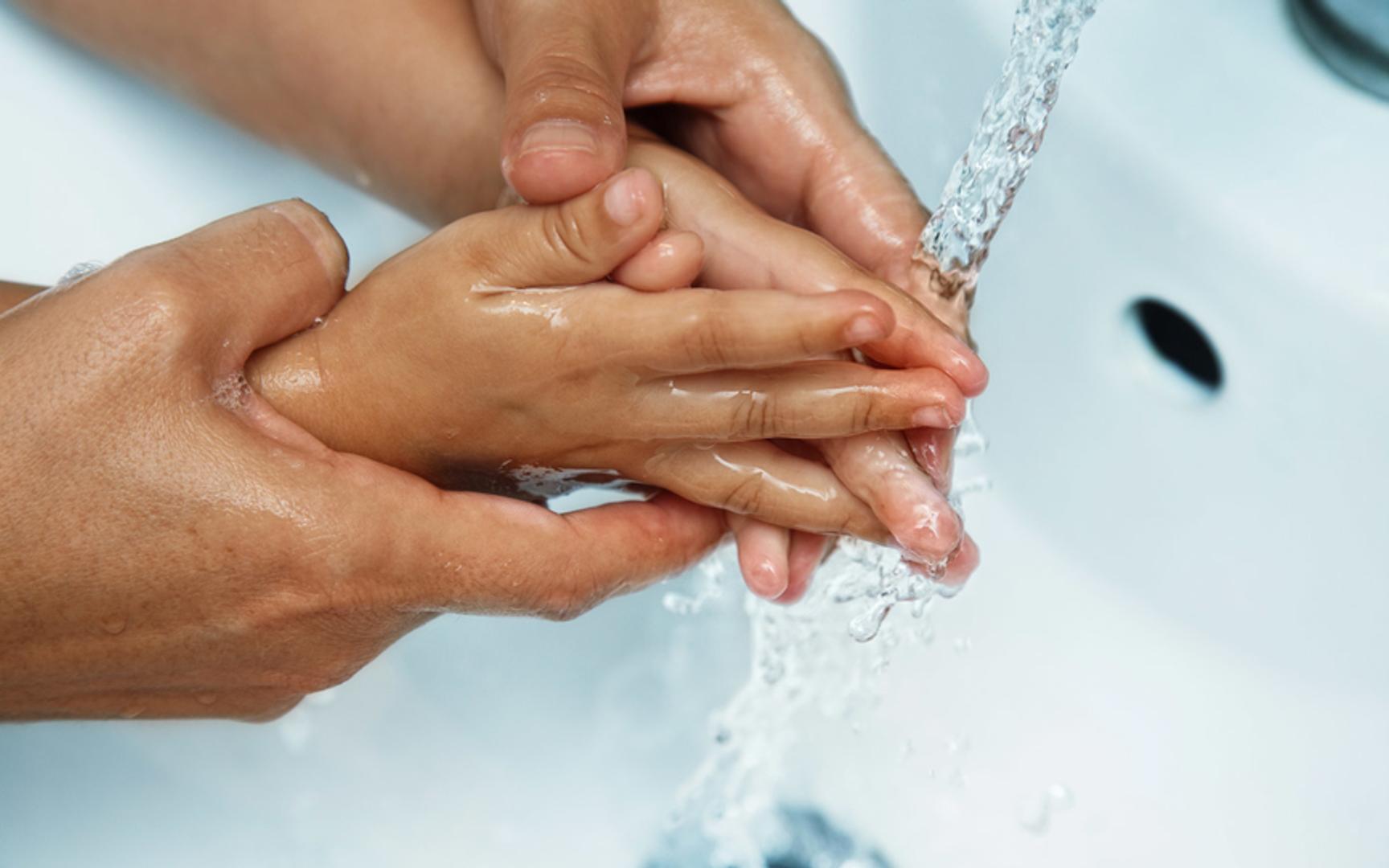 Voksen og barn som vasker hendene under krana