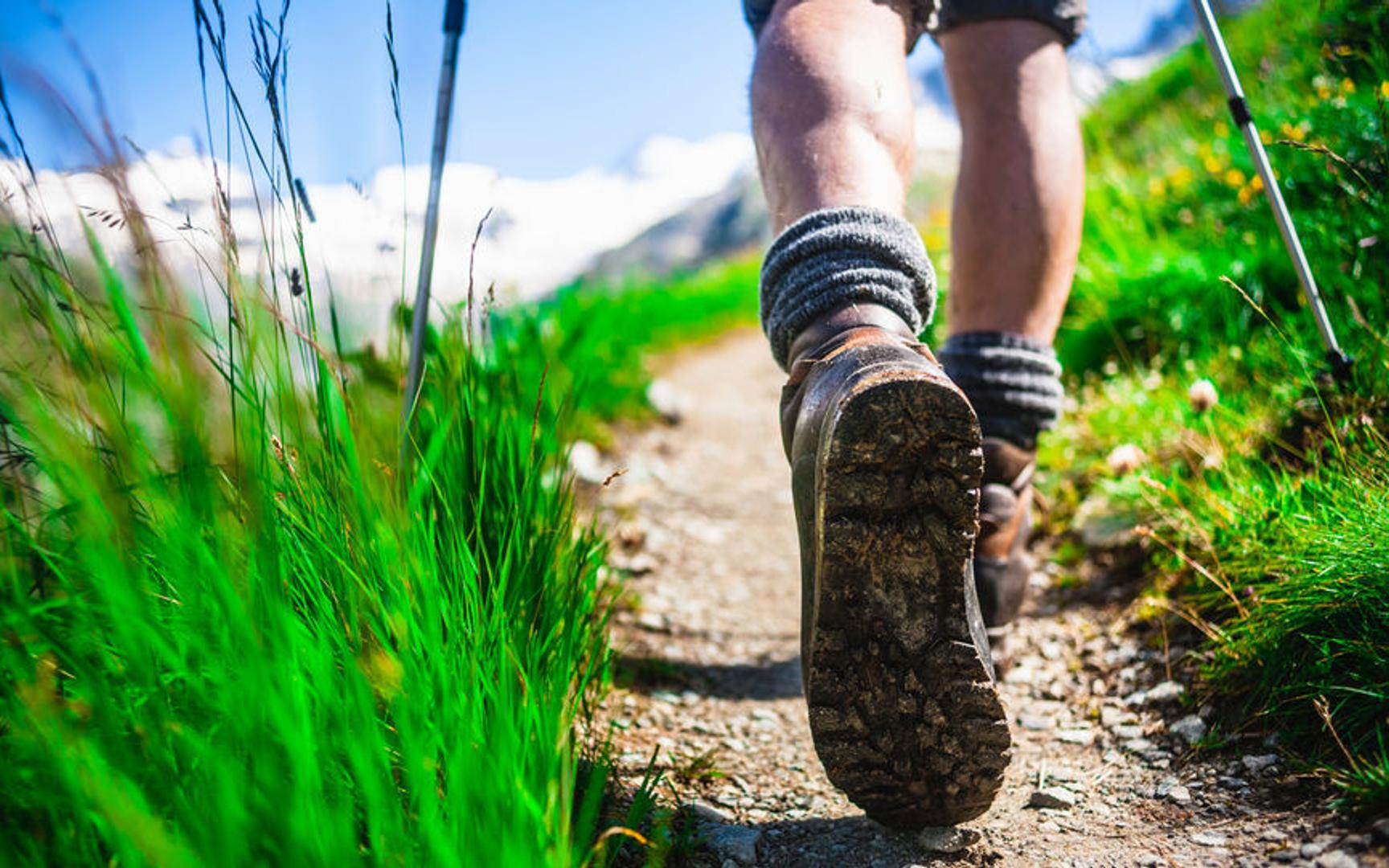 To føtter med tursko og sokker går på en sti med grønt gress rundt