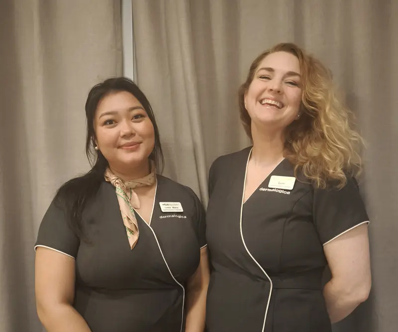 To smilende damer i lik uniform og navnskilt.