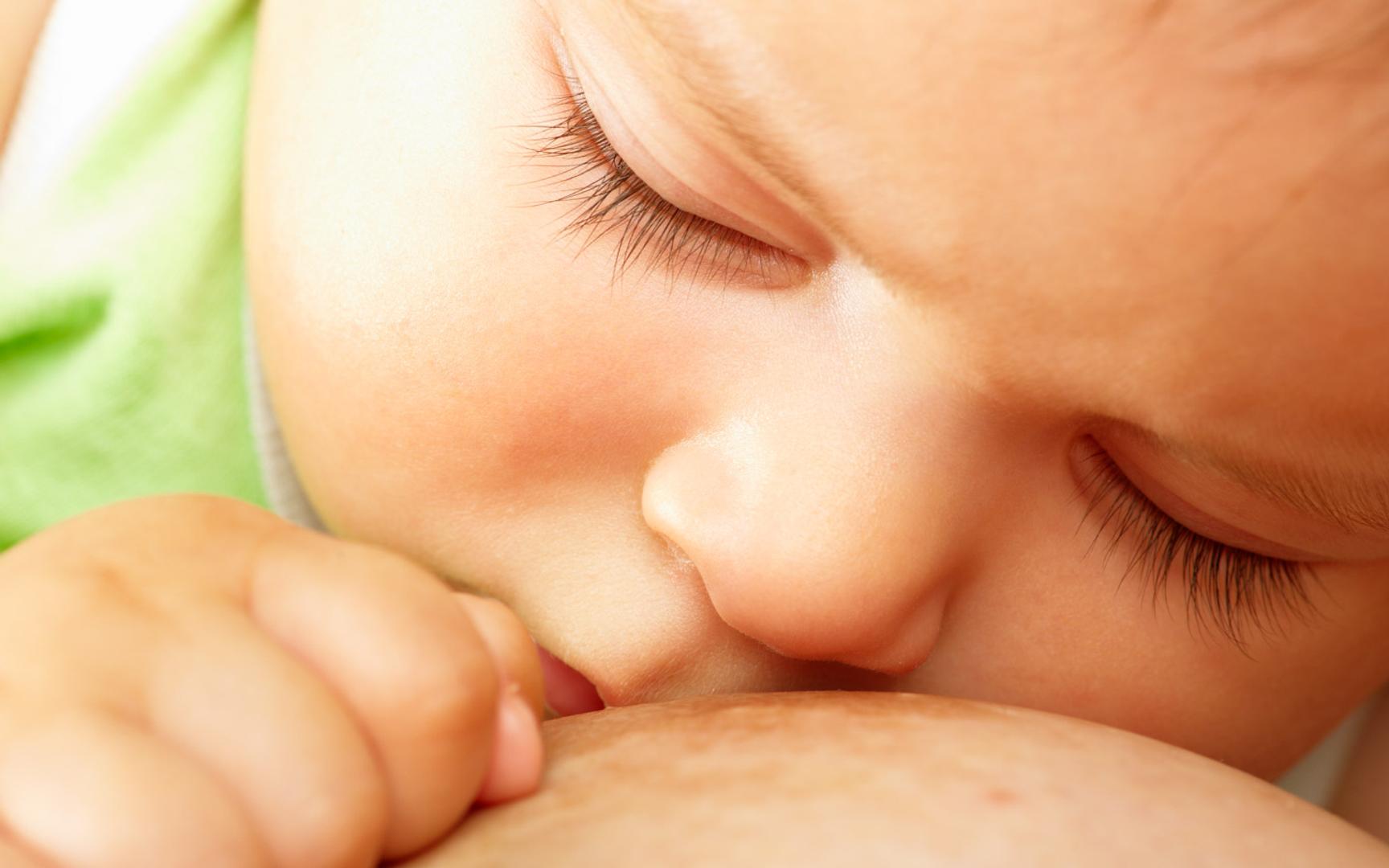 Bilde av baby som sover ved brystet.