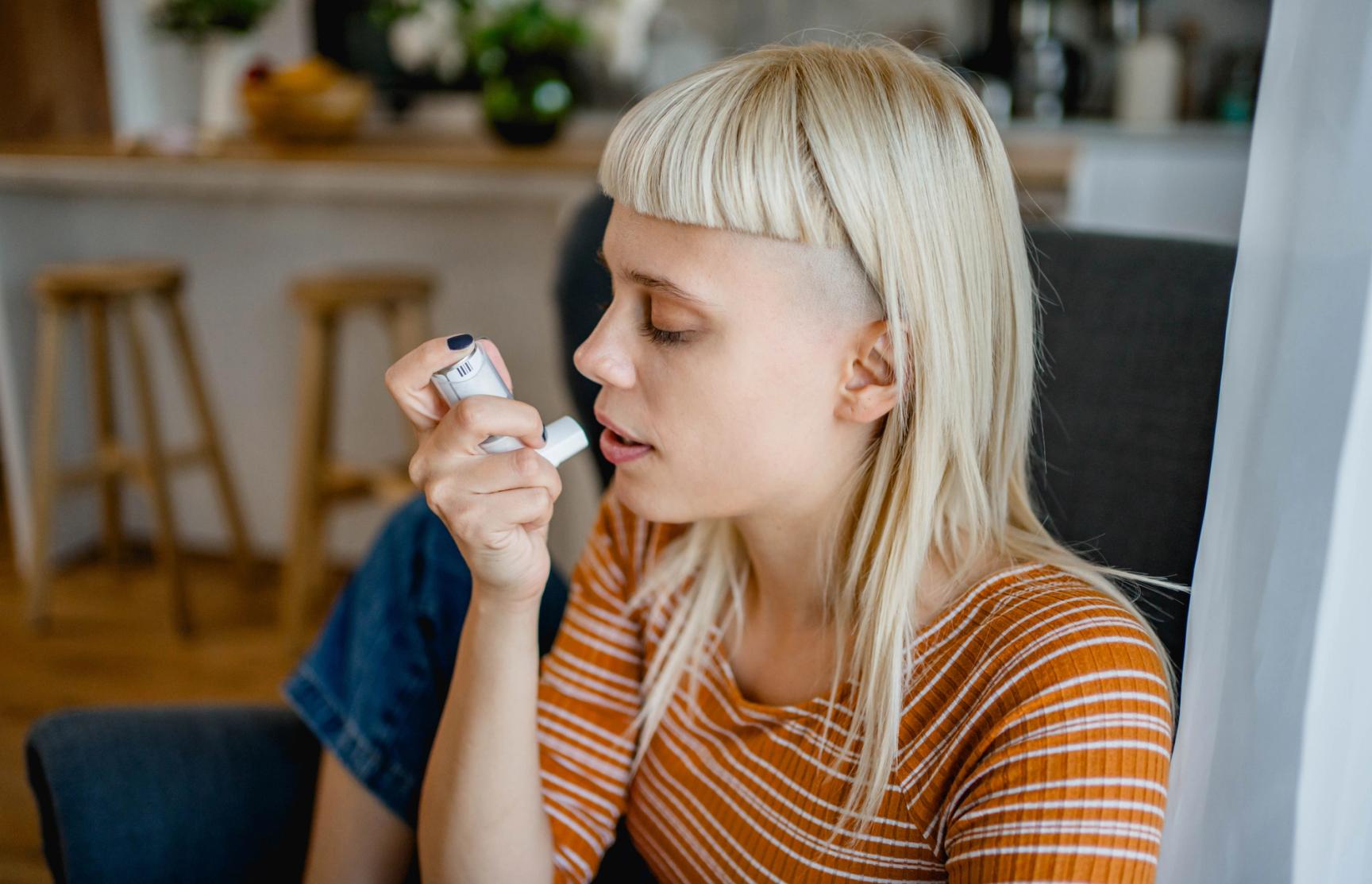 Kvinne med pannelugg som bruker en inhalator