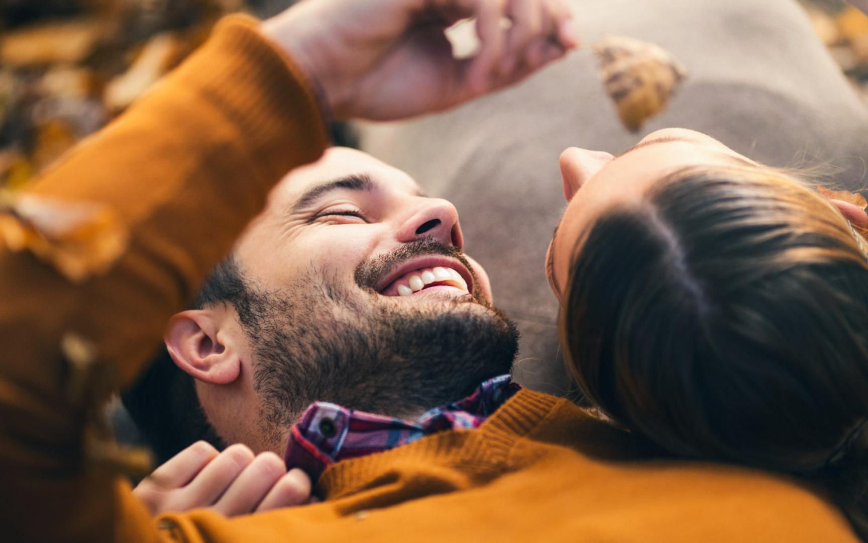 Bilde av en smilende mann og en kvinner som ligger og ser på hverandre.