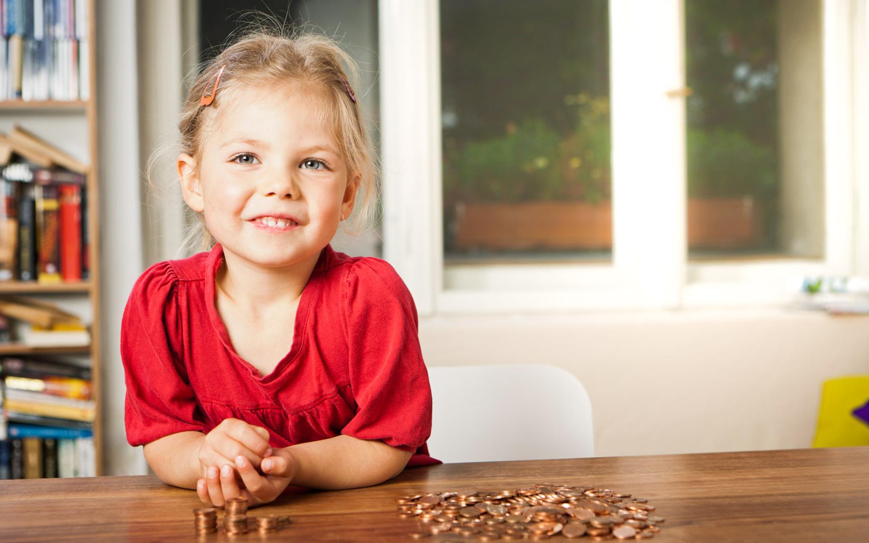 Liten jente i rød genser som sitter og teller mynter
