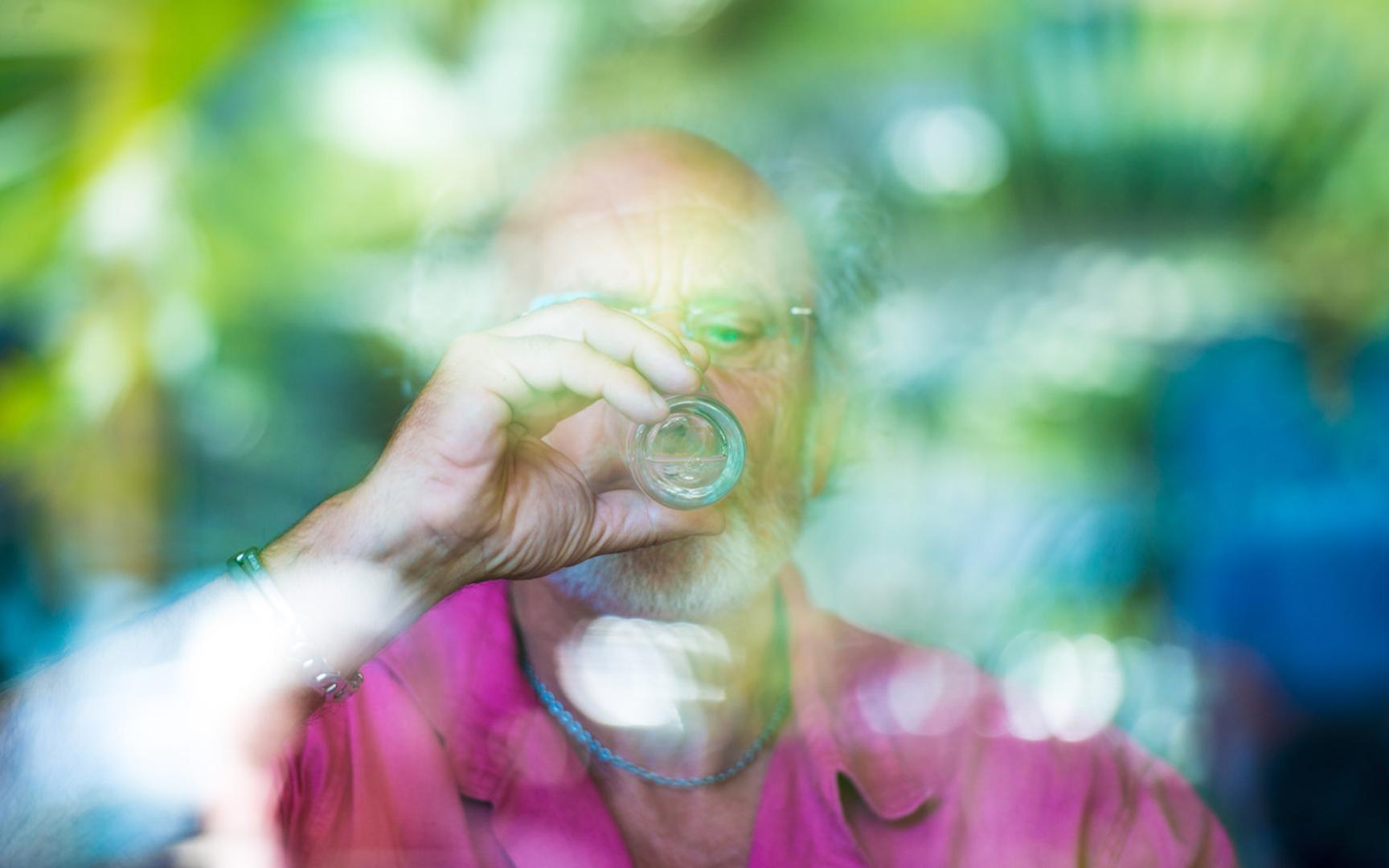 Eldre mann drikker av et glass