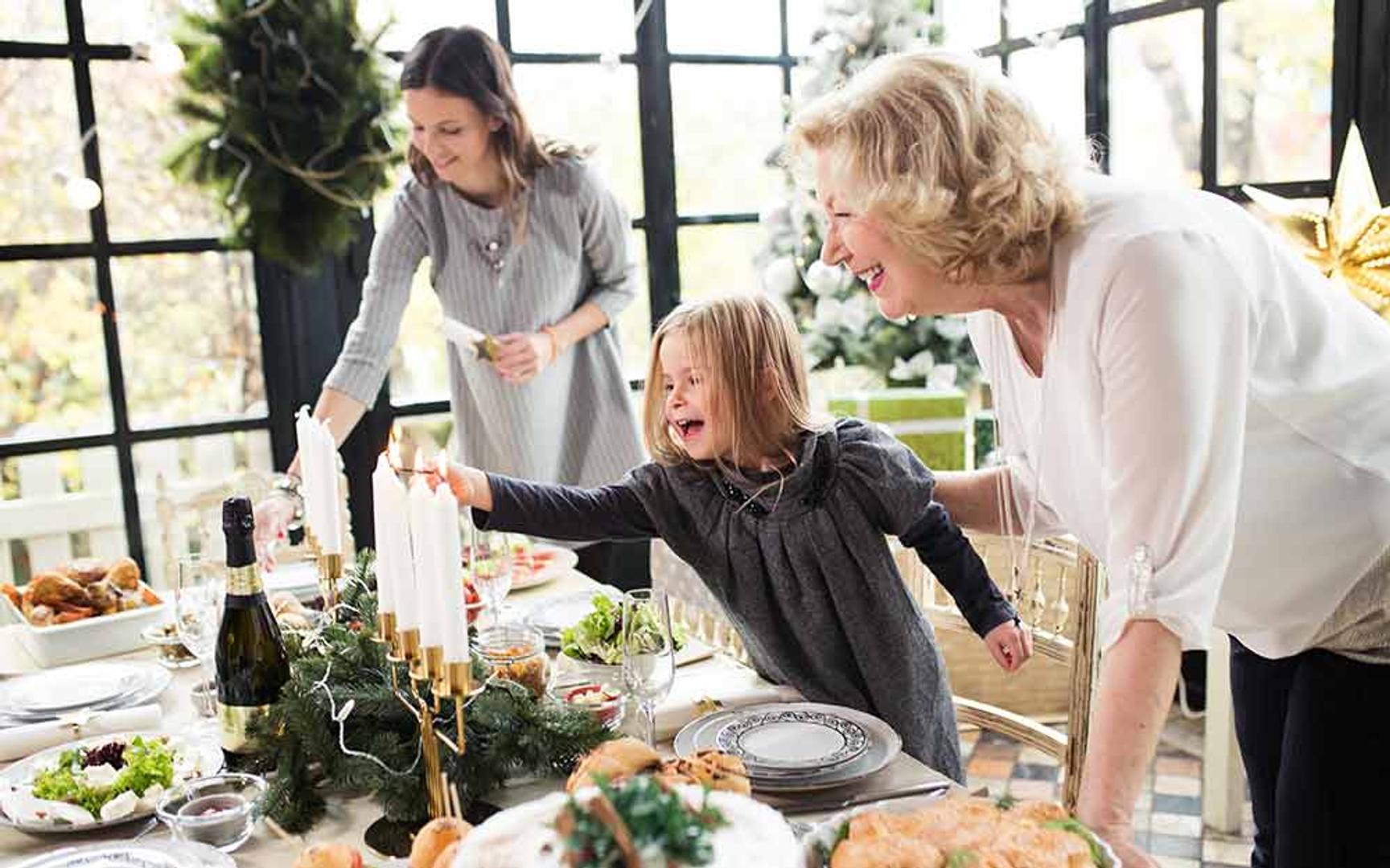 Eldre dame, mor og datter dekker og pynter spisebordet til jul.